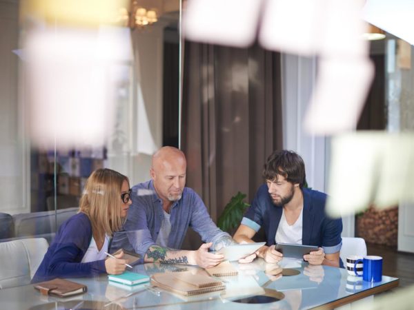 Professional designers Mature businessman with touchpad presenting his colleagues fresh ideas